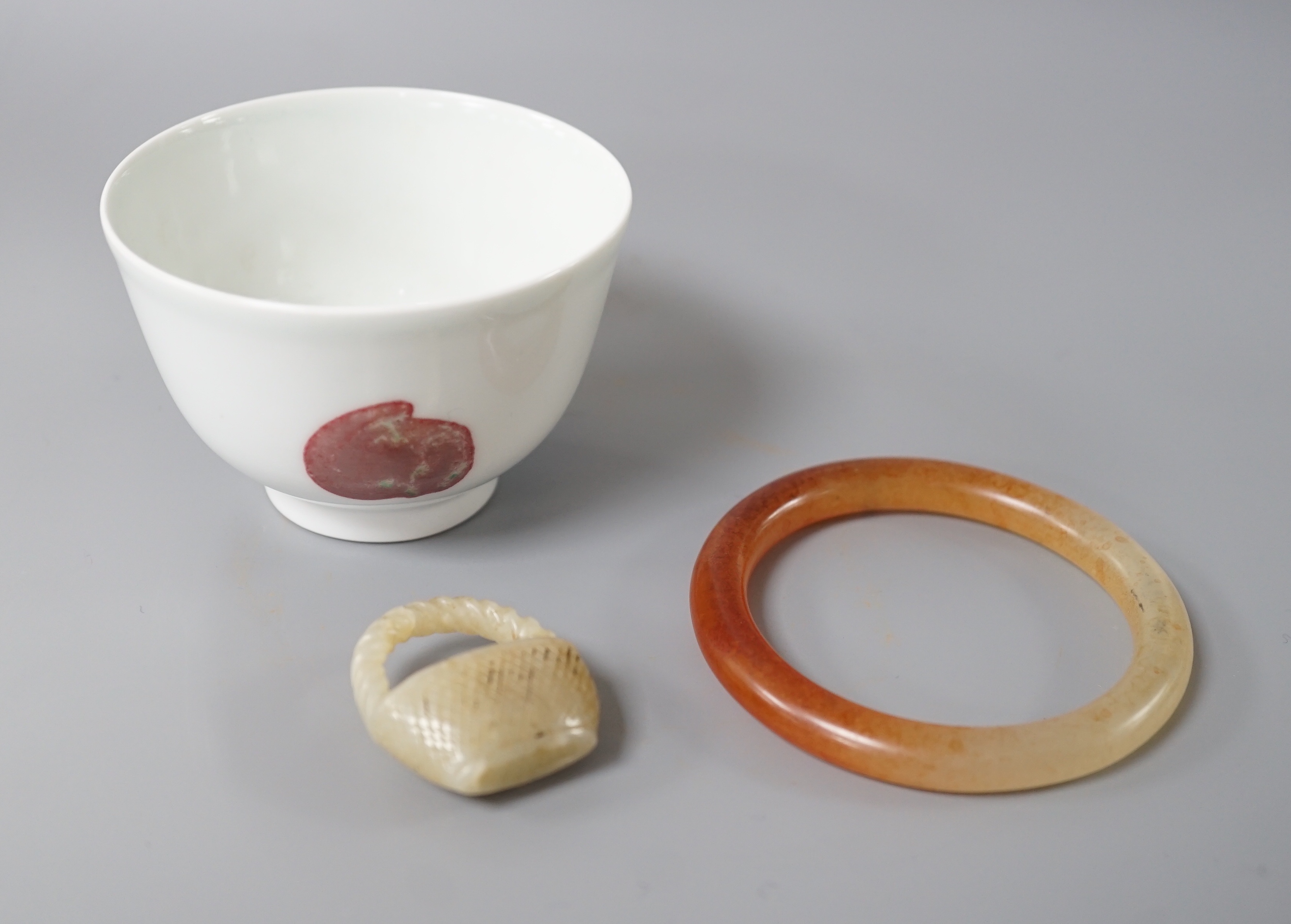 A Chinese porcelain teabowl with ‘fruit’ decoration, an agate bangle and a similar ‘basket’ carving.